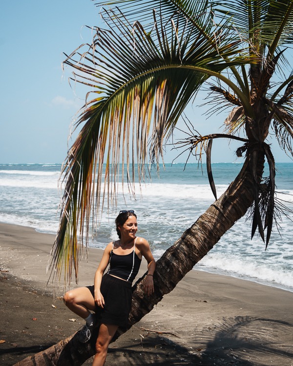 a woman sitting on a palm tree in Cahuita National Park