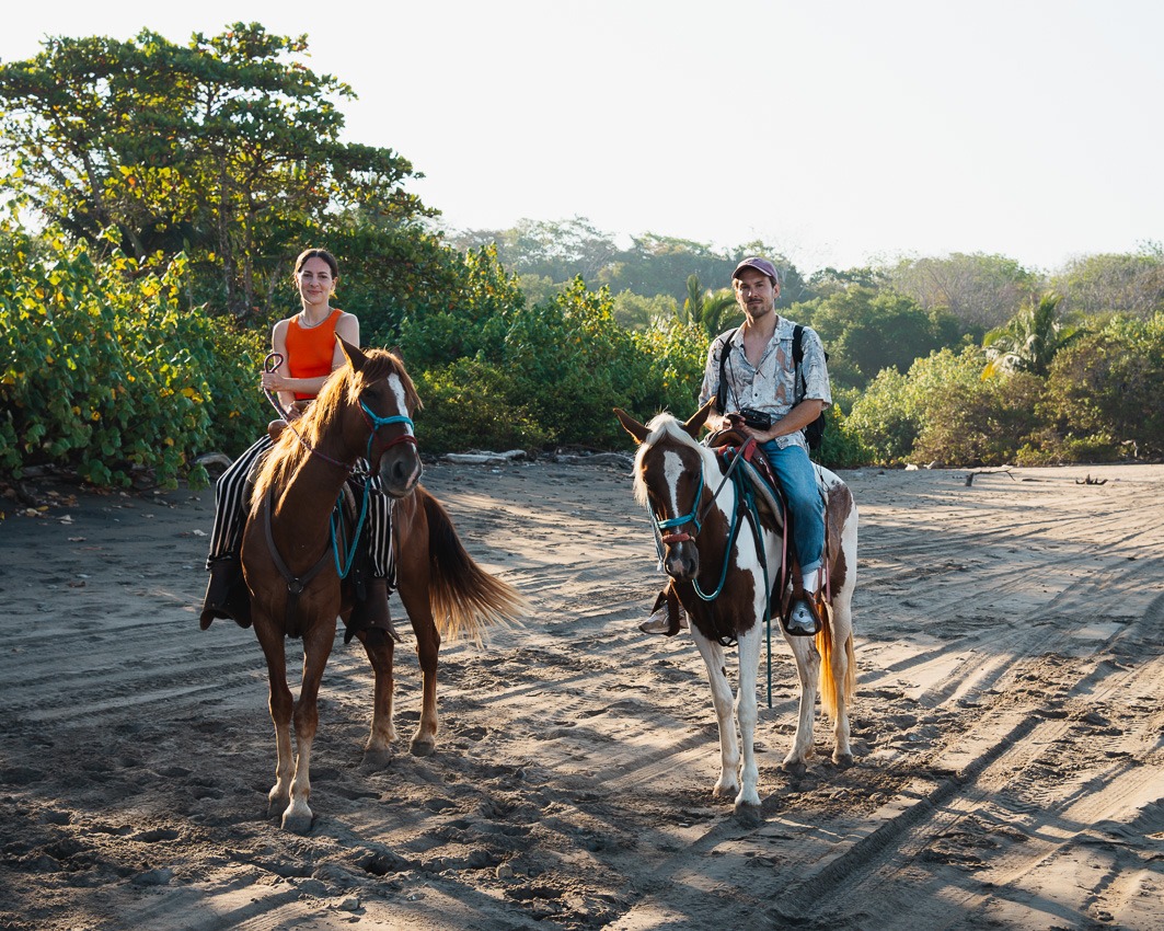 a woman and a man on a horse in Costa Rica at the beach