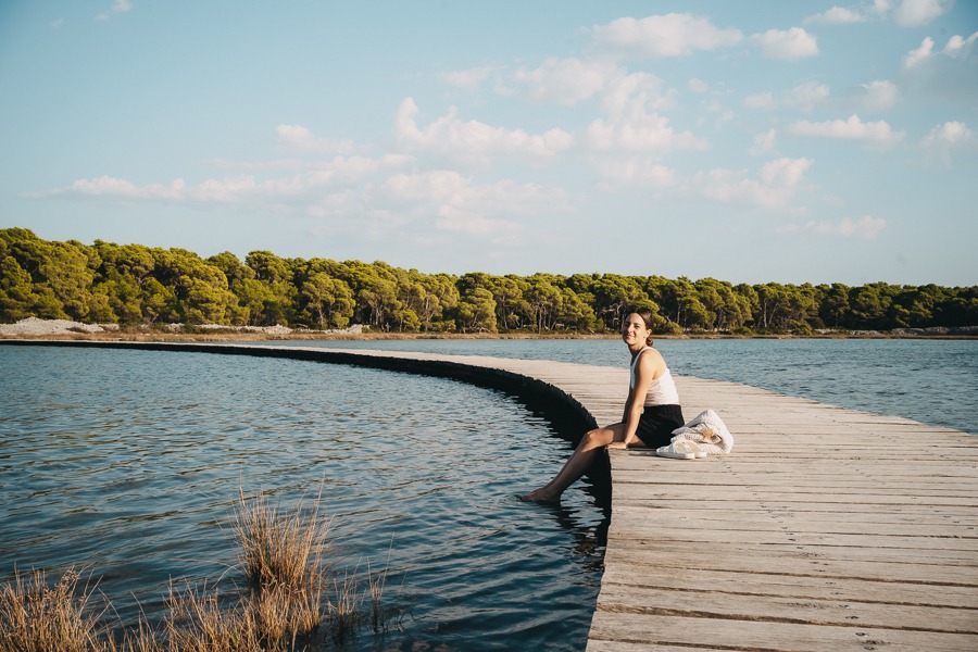 A young woman sits on the pier at the St. Ante sea channel in Šibenik, Croatia.