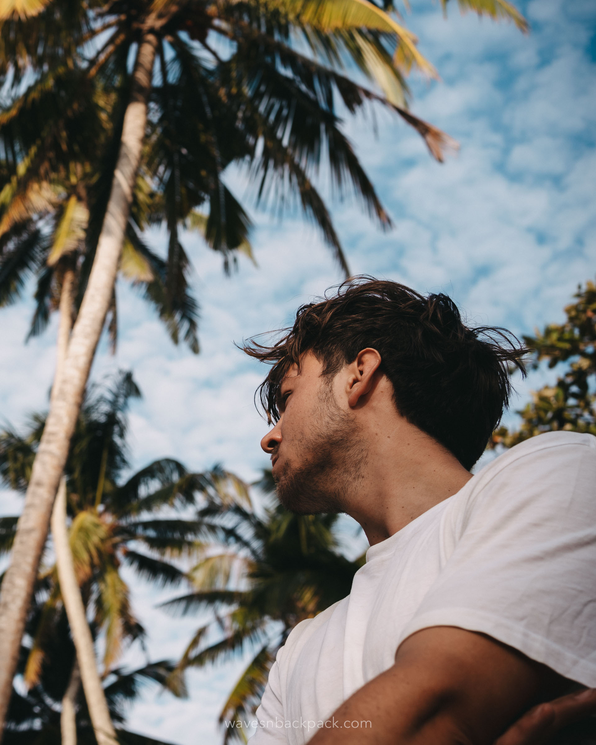 a young man standing in front of palm trees