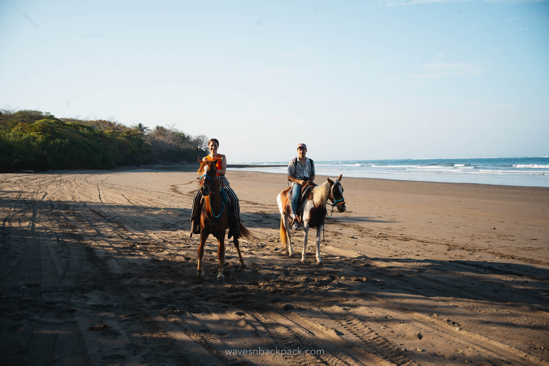 a couple riding horses on the beach in Costa Rica